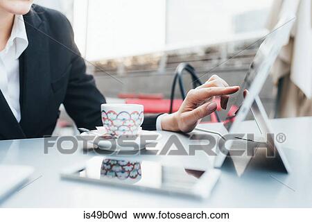 Stock Image - Businesswoman using digital tablet in coffee shop. Fotosearch