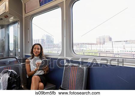 Stock Image - Businesswoman using digital tablet on train. Fotosearch