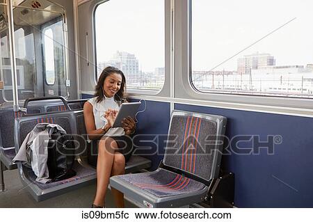Stock Image - Businesswoman using digital tablet on train. Fotosearch