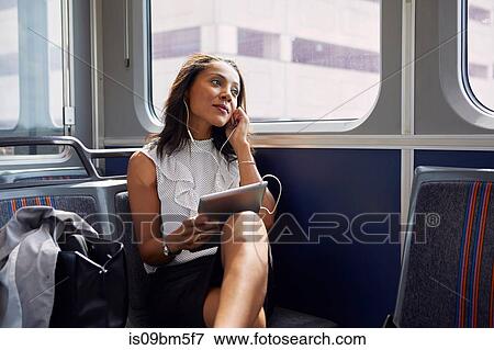 Stock Photo - Businesswoman using digital tablet on train. Fotosearch