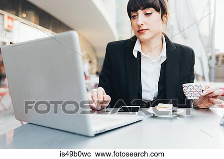 Businesswoman using laptop in coffee shop, Milan, Italy View Large Photo Image Stock Image - Businesswoman using laptop in coffee shop, Milan, Italy. Fotosearch
