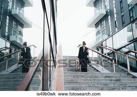 Businesswoman using mobile and carrying trolley luggage, Milan, Italy View Large Photo Image Stock Image - Businesswoman using mobile and carrying trolley luggage, Milan, Italy. Fotosearch
