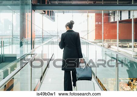 Businesswoman using mobile and pulling trolley luggage, Milan, Italy View Large Photo Image Stock Image - Businesswoman using mobile and pulling trolley luggage, Milan, Italy. Fotosearch