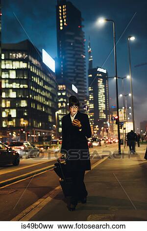 Businesswoman using mobile phone and pulling trolley luggage, Milan, Italy View Large Photo Image Stock Photo - Businesswoman using mobile phone and pulling trolley luggage, Milan, Italy. Fotosearch