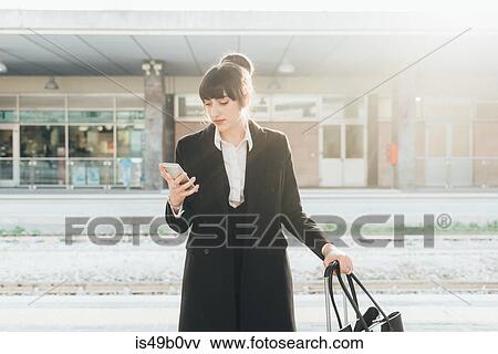 Businesswoman using mobile phone in train station, Milan, Italy View Large Photo Image Stock Photo - Businesswoman using mobile phone in train station, Milan, Italy. Fotosearch
