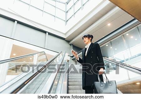 Businesswoman using mobile phone on escalator, Milan, Italy View Large Photo Image Stock Image - Businesswoman using mobile phone on escalator, Milan, Italy. Fotosearch