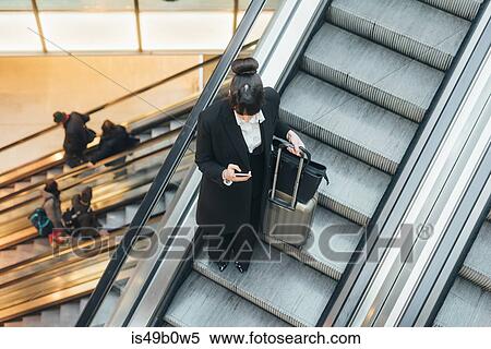 Businesswoman using mobile phone on escalator, Milan, Italy View Large Photo Image Stock Photography - Businesswoman using mobile phone on escalator, Milan, Italy. Fotosearch
