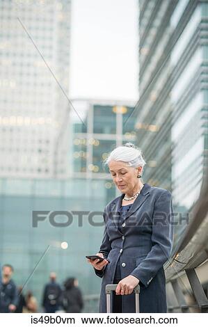 Picture - Businesswoman using mobile phone, Canary Wharf, London, UK. Fotosearch