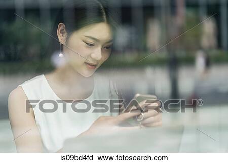 Businesswoman using smartphone and laptop, viewed through window View Large Photo Image Stock Image - Businesswoman using smartphone and laptop, viewed through window. Fotosearch