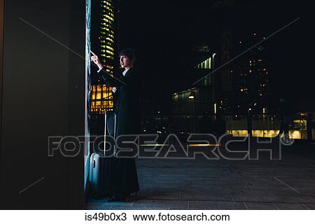 Stock Image - Businesswoman using ticket machine, Milan, Italy. Fotosearch
