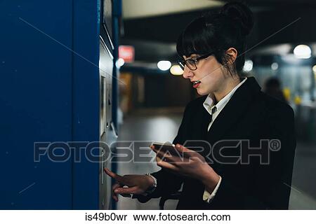 Stock Photography - Businesswoman using ticket machine, Milan, Italy. Fotosearch
