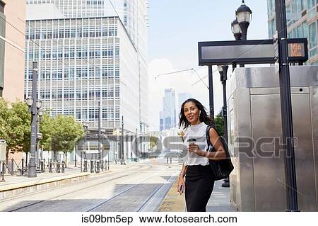 Stock Photography - Businesswoman waiting on light rail platform. Fotosearch