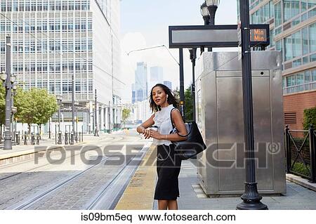 Stock Photography - Businesswoman waiting on light rail platform. Fotosearch
