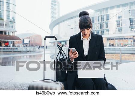 Businesswoman with trolley luggage using mobile phone and digital tablet, Milan, Italy View Large Photo Image Stock Image - Businesswoman with trolley luggage using mobile phone and digital tablet, Milan, Italy. Fotosearch