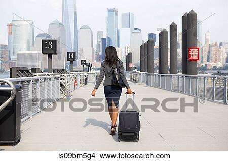 Businesswoman with wheeled luggage on ferry pier View Large Photo Image Picture - Businesswoman with wheeled luggage on ferry pier. Fotosearch