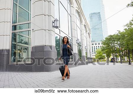 Businesswoman with wheeled luggage View Large Photo Image Stock Photo - Businesswoman with wheeled luggage. Fotosearch