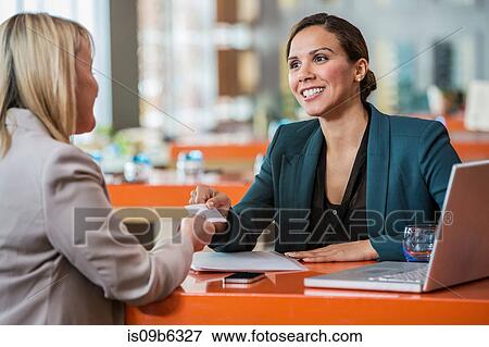 Businesswomen making introductions in cafe View Large Photo Image Stock Photo - Businesswomen making introductions in cafe. Fotosearch