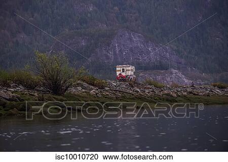 Stock Image - Camper carrying motorcycle parked by Squamish River, Howe Sound, Canada. Fotosearch