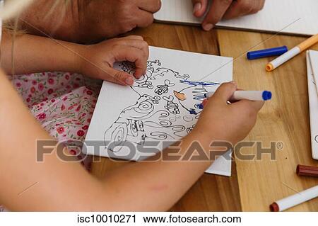 Stock Image - Child colouring a picture on a table. Fotosearch