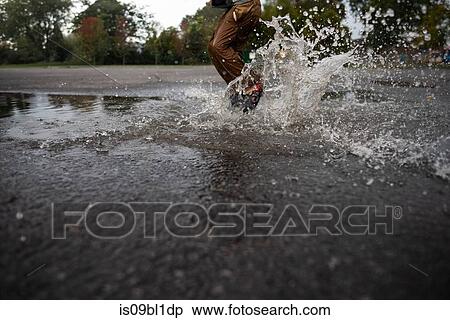 Stock Photography - Child splashing in puddle on road. Fotosearch