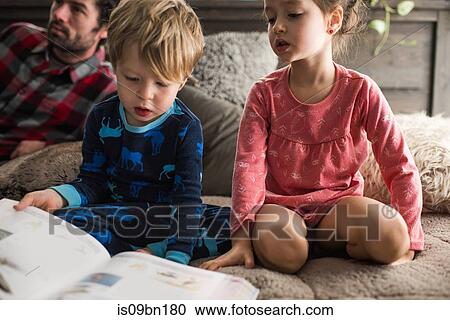 Children reading book at home, father in background View Large Photo Image Stock Image - Children reading book at home, father in background. Fotosearch