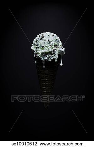 Stock Image - Chocolate chip mint ice-cream cone with melted droplets against black background. Fotosearch