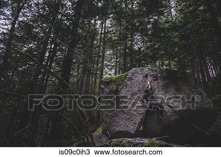 Stock Image - Climber bouldering in forest, Squamish, Canada. Fotosearch