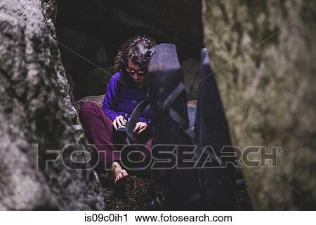Stock Image - Climber putting on shoes between rocks, Squamish, Canada. Fotosearch