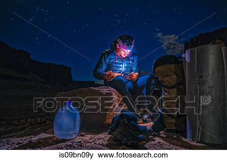 Stock Photo - Climber reading book on rock climbing route, Canyonlands National Park, Moab, Utah, USA. Fotosearch