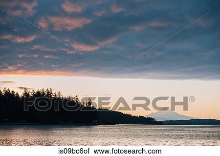 Stock Image - Clouds over scenic view of mountains over water, Bainbridge, Washington, United States. Fotosearch