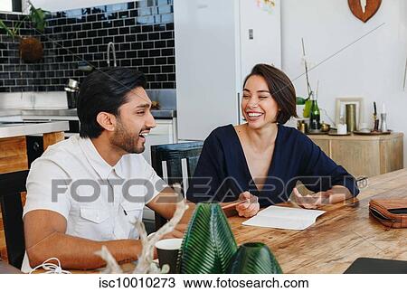 Stock Image - Colleagues having discussion in office. Fotosearch