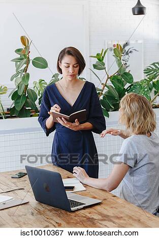 Stock Photo - Colleagues having discussion in office. Fotosearch