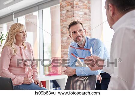 Stock Photograph - Colleagues having discussion in office. Fotosearch
