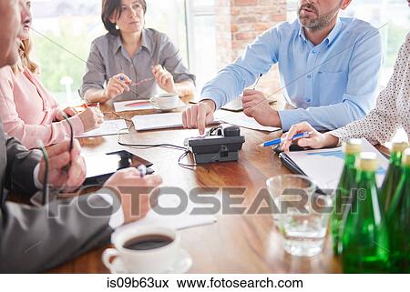 Stock Photo - Colleagues having discussion in business meeting. Fotosearch