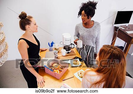 Colleagues in coffee area sharing box of doughnuts View Large Photo Image Stock Image - Colleagues in coffee area sharing box of doughnuts. Fotosearch