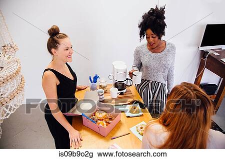 Colleagues in coffee area sharing box of doughnuts View Large Photo Image Stock Image - Colleagues in coffee area sharing box of doughnuts. Fotosearch