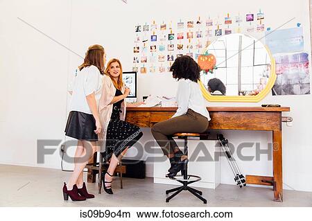 Picture - Colleagues in creative studio at desk having discussion. Fotosearch