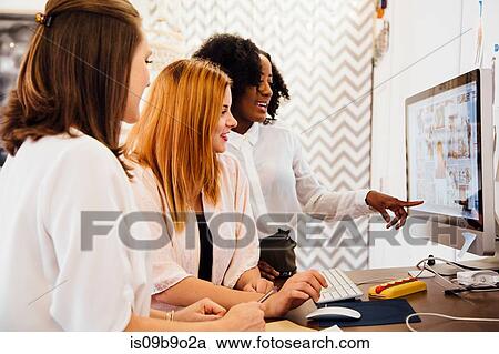 Stock Image - Colleagues in creative studio having discussion, using computer. Fotosearch