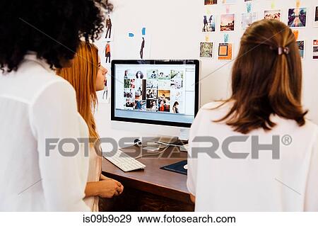 Stock Photo - Colleagues in creative studio having discussion, using computer. Fotosearch