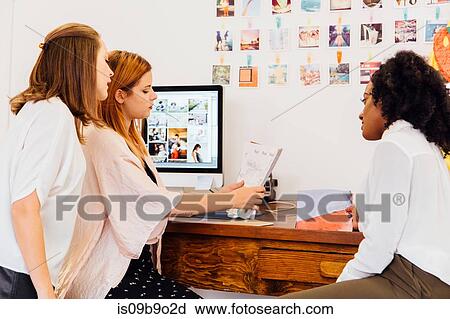 Colleagues in creative studio discussing paperwork View Large Photo Image Stock Image - Colleagues in creative studio discussing paperwork. Fotosearch