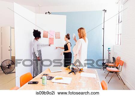 Stock Image - Colleagues in creative studio discussing swatches. Fotosearch