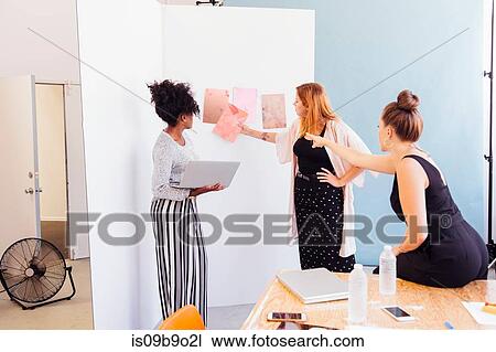 Stock Image - Colleagues in creative studio discussing swatches. Fotosearch