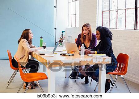 Stock Image - Colleagues in industrial office building working at desk. Fotosearch