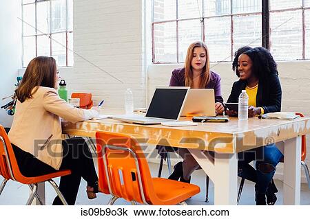 Stock Image - Colleagues in industrial office building working at desk. Fotosearch