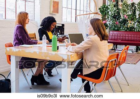 Stock Image - Colleagues in industrial office building working at desk. Fotosearch