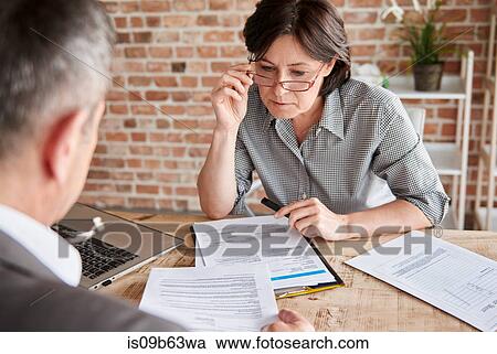 Colleagues in office discussing paperwork View Large Photo Image Stock Image - Colleagues in office discussing paperwork. Fotosearch
