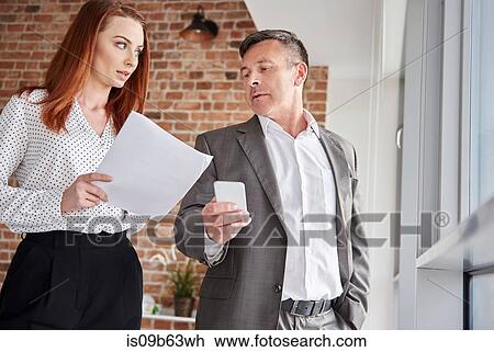 Colleagues in office discussing paperwork View Large Photo Image Stock Image - Colleagues in office discussing paperwork. Fotosearch