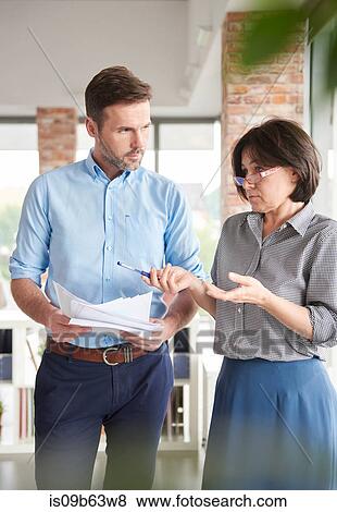 Colleagues in office discussing paperwork View Large Photo Image Stock Photo - Colleagues in office discussing paperwork. Fotosearch