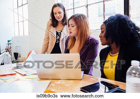 Stock Photograph - Colleagues in office discussing paperwork. Fotosearch