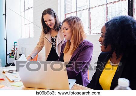 Stock Photograph - Colleagues in office discussing paperwork. Fotosearch